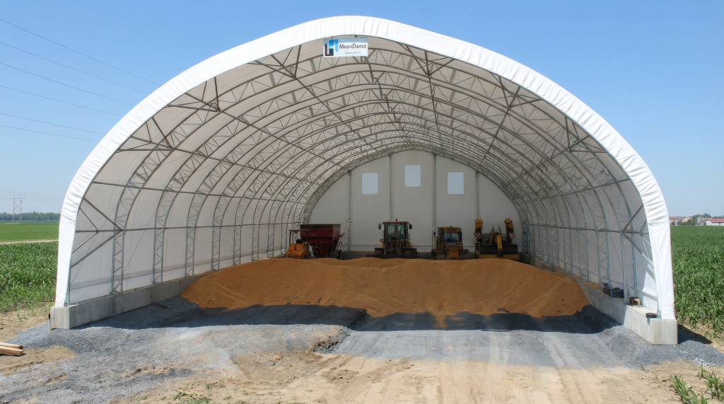 Interior view of a wide-span fabric grain storage building featuring galvanized steel trusses and high-clearance ceilings for heavy machinery.